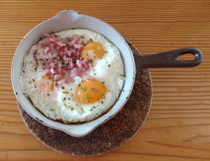 Skillet with two fried eggs topped with chopped ham