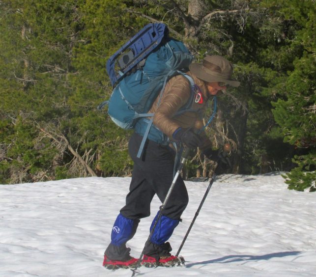 Woman with backpack hiking on snow