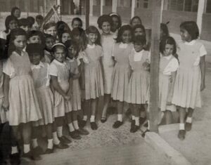 Large group of girls in school uniforms stand with their teacher