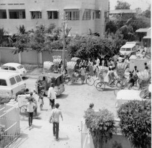 School lets out with mass of bicycle rickshaws and two Volkswagons in Dacca, East Pakistan