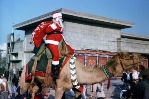 Man dressed in red Santa suit sitting on a camel