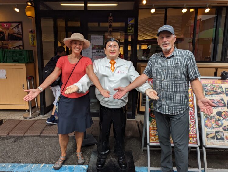 Woman and man with life size statue of a waiter in front of a cafe