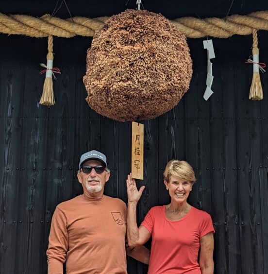 Large brown cedar ball hanging over and man and woman