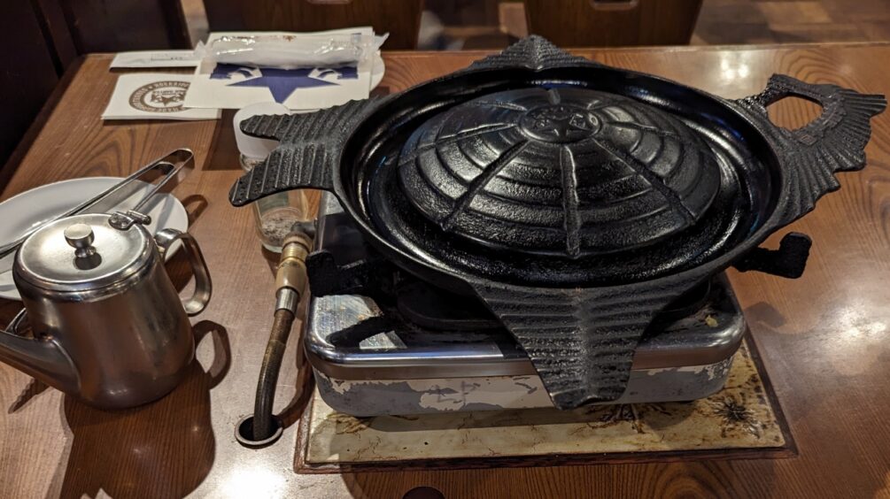 Large black domed metal grill for cooking meats and vegetables at the table