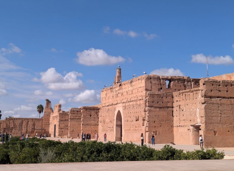 Vast palace made from tall pink stucco walls. A sunken orchard is visible. 