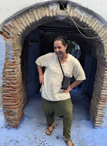 Moroccan man strikes a fanciful pose under a brick archway