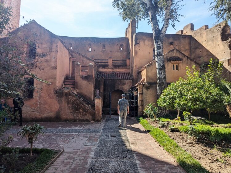 Old pink stucco bulding with a courtyard with trees and shrubs