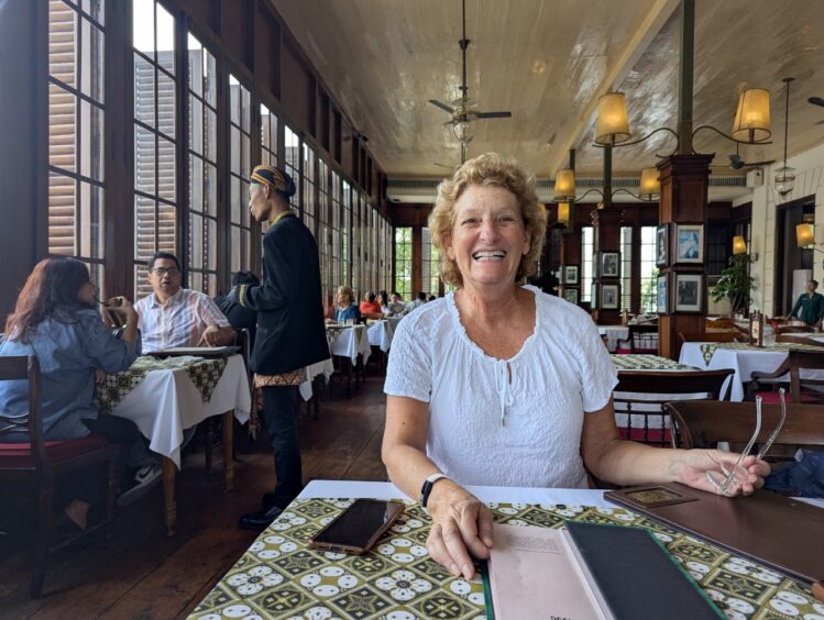 Western woman seated at a restaurant with large paned windows in an elegant setting. 