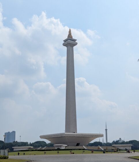 Tall monument topped with gold metal flame sculpture. 
