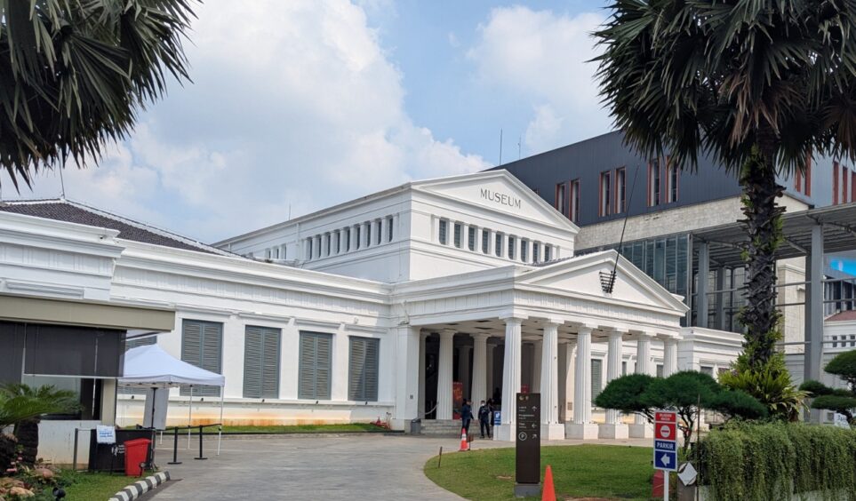 White building with columns and circular driveway.
