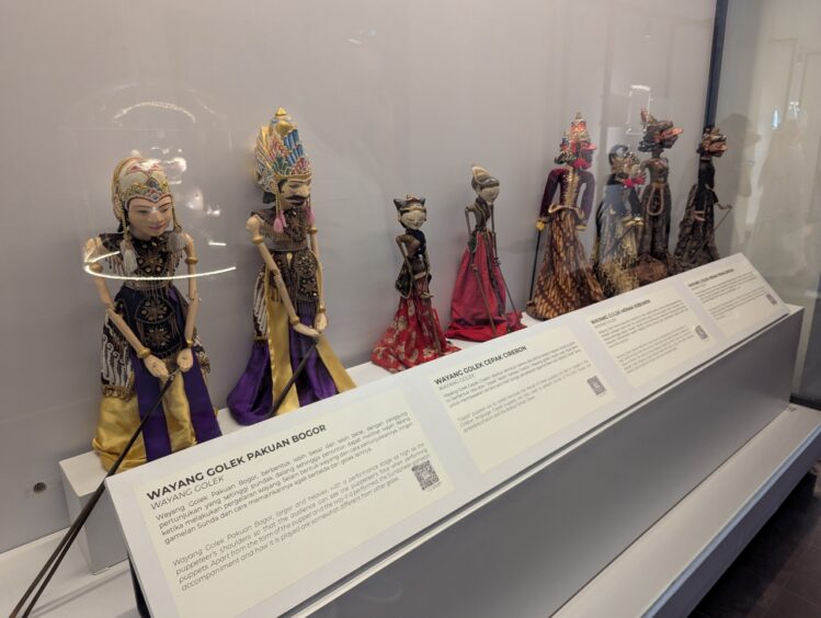 A display with eight carved wooden puppets. 