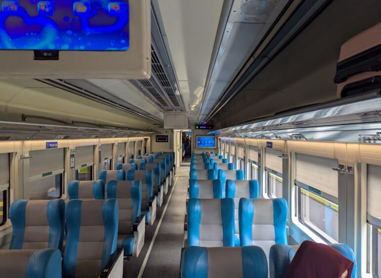 Interior of empty train with blue and gray seats in executive class