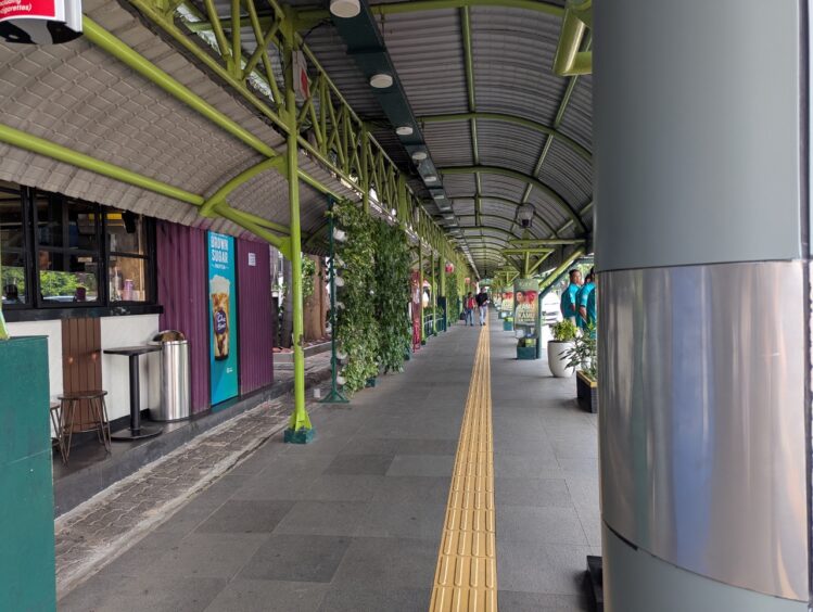 A quiet scene showing clean pavement and appealing greenery at the Gambir station