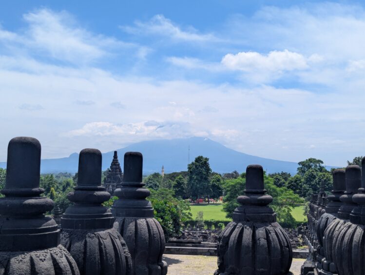 Stupas in the foreground of the Prambanan Temple with Mt. Merapi in the background.