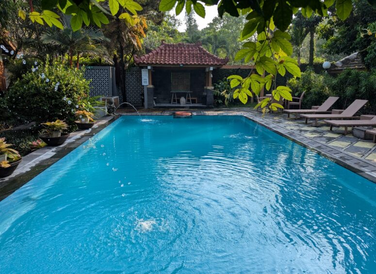 Pool with clear water and fountains surrounded by lush, tropical foliage