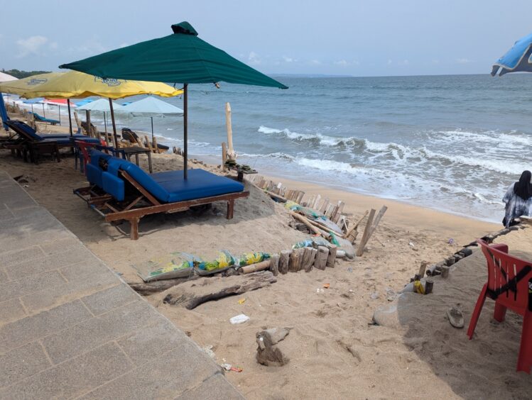Thin strip of beach sand with reinforcements makde of wood and sandbags to hold the sand against erosion