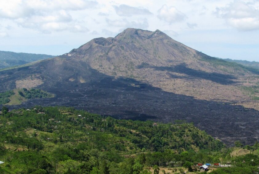 Large volcano with a wide strip of black lava between dense foliage and brown section from a previous flow