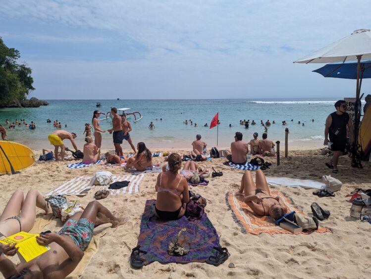 Crowded beach with many people standing in the water